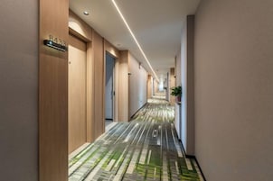Corredor de hotel com portas de madeira, carpete estampado e uma placa indicando o número do quarto 8433.