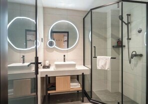 A modern bathroom with two sinks, a glass shower enclosure, and circular mirrors.