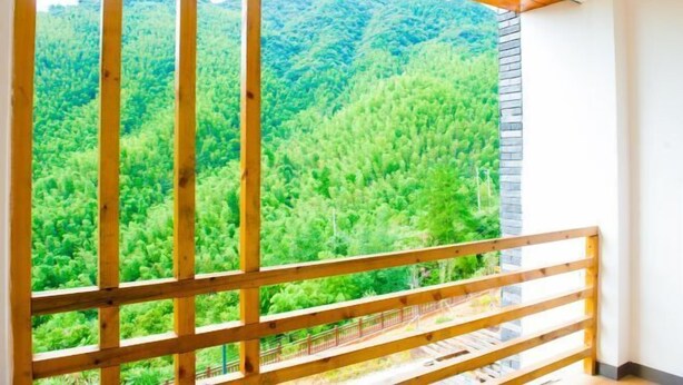 A room with a wooden balcony overlooking a dense forest. - Jinying Shanzhuang Hotel (Hengshan County)