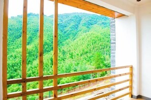 A room with a large window overlooking a forested mountain area. - Jinying Shanzhuang Hotel (Hengshan County)