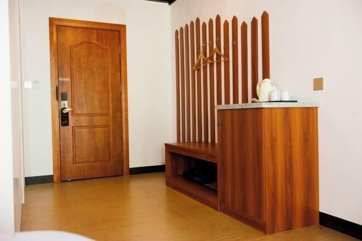 A wooden door, a wooden partition with vertical slats, and a small shelf with a kettle and teapot.