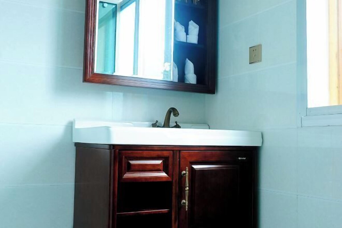 A bathroom with a white sink, wooden cabinets, and a mirror above the sink.
