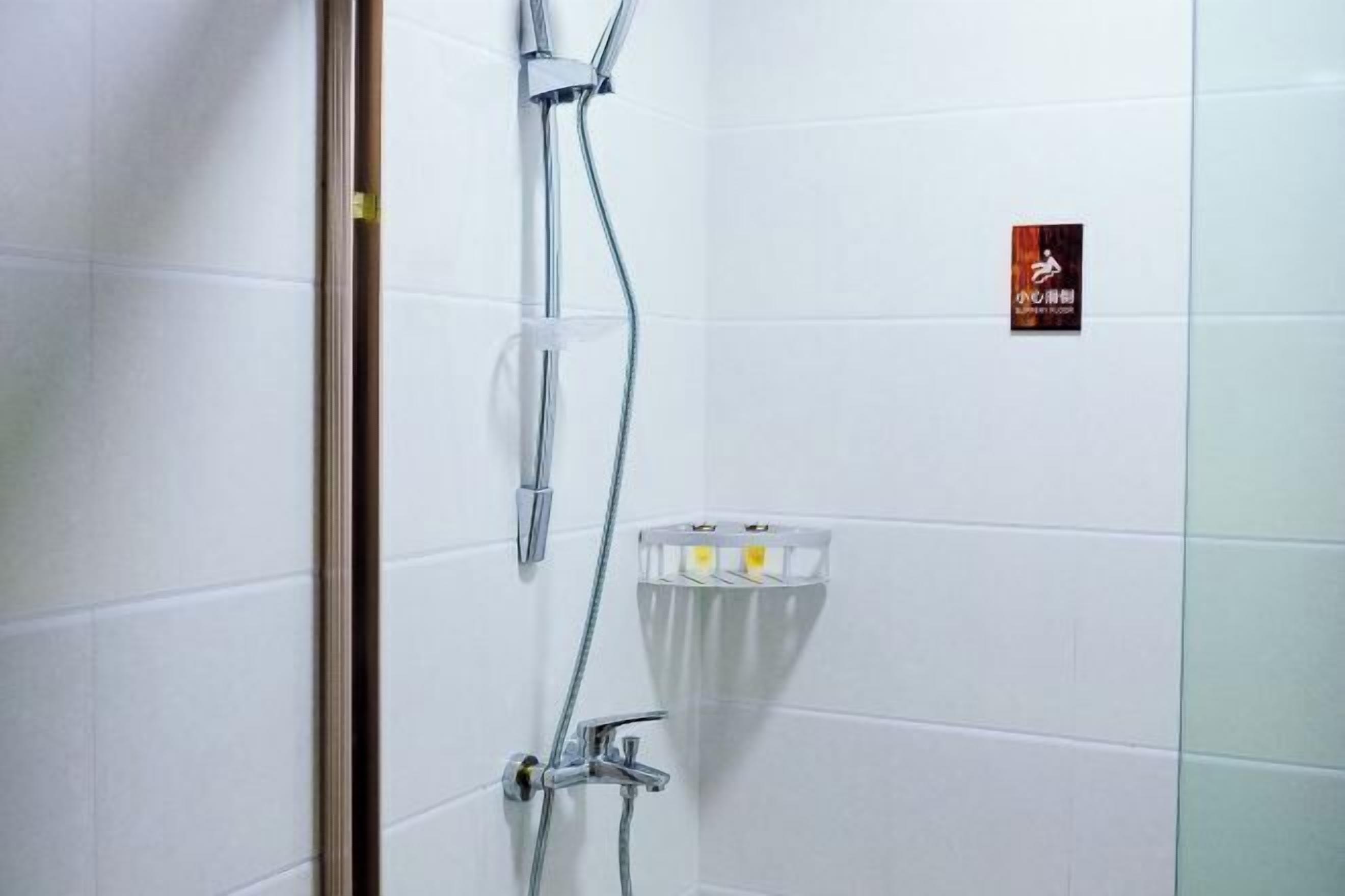 A shower with a glass enclosure, a towel rack, and a sign on the wall.