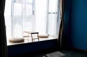 A room with a window, a small wooden table, and two round cushions on the windowsill.