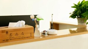 Un comptoir d’accueil avec une boîte en bois, un vase avec une fleur, une boîte de mouchoirs et une petite plante en pot.