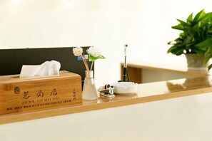 A reception desk with a wooden box, a vase with flowers, a small plant, and a white object on the counter. - Mingtaoju Theme Inn (Zixing)