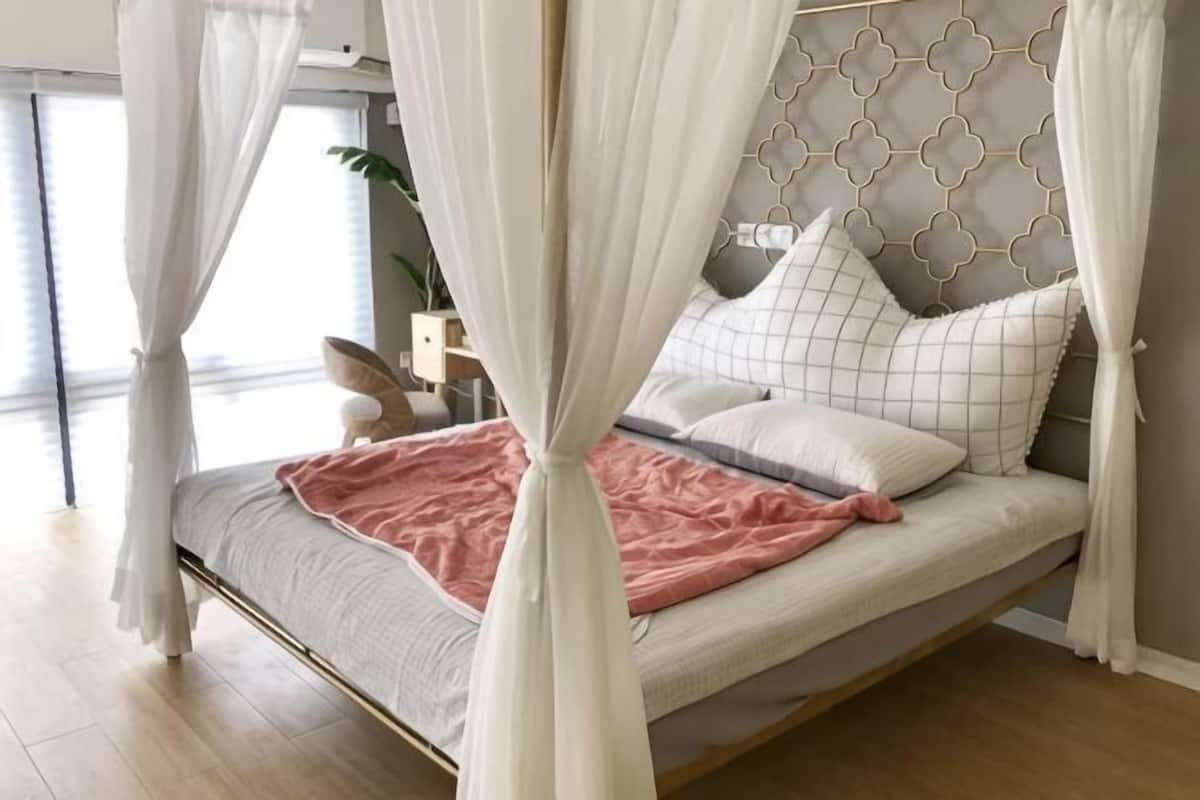 Ein Bett mit Baldachin, ein Nachttisch und eine Pflanze.