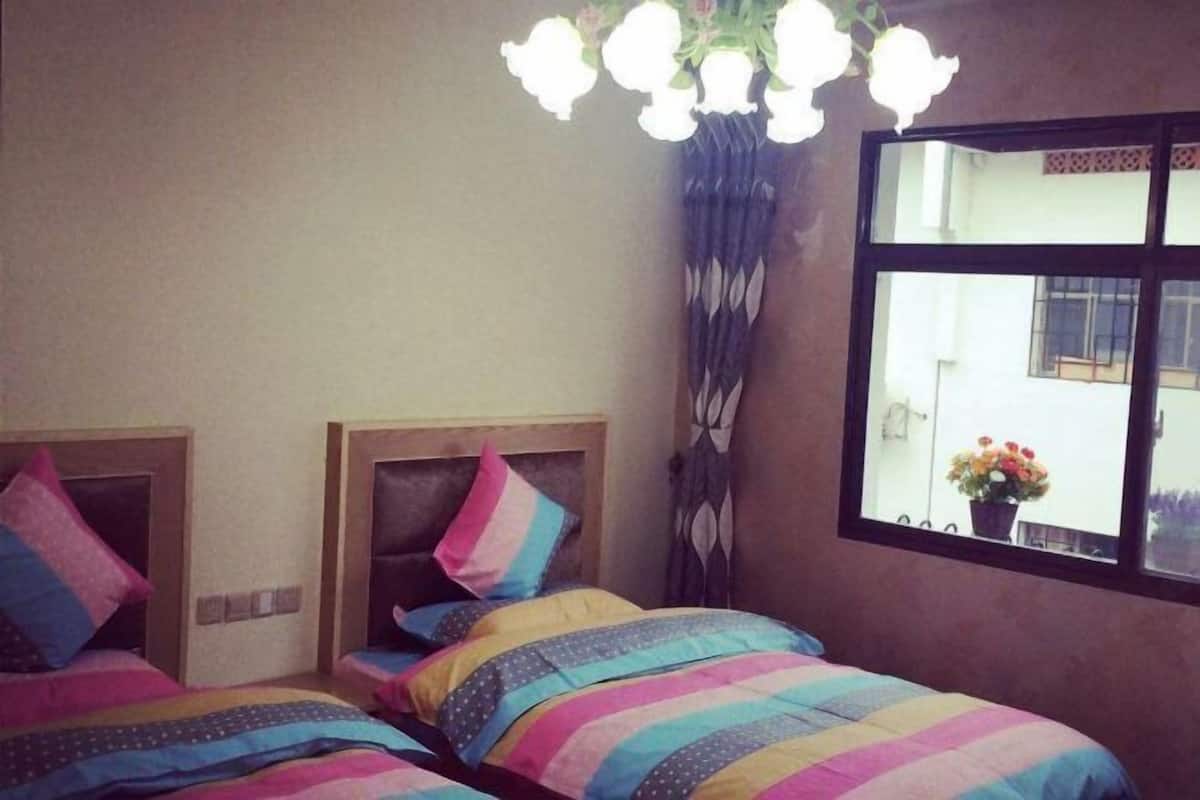 Ein Zimmer mit zwei Betten, einem Fenster mit Blick und einer Kristallleuchtre.