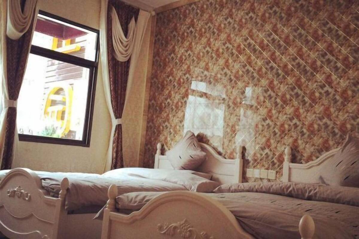 Ein Schlafzimmer mit zwei Betten, einem Fenster mit Vorhängen und einer Wand mit Muster.