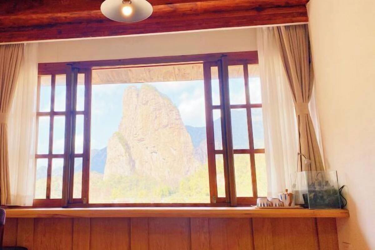 Une pièce dotée d’une grande fenêtre, de poutres apparentes et offrant une vue sur une montagne.