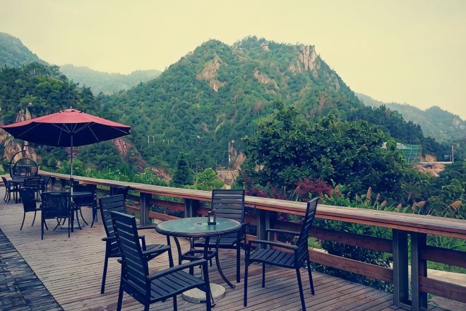 An outdoor seating area with tables and chairs, overlooking a mountainous landscape.