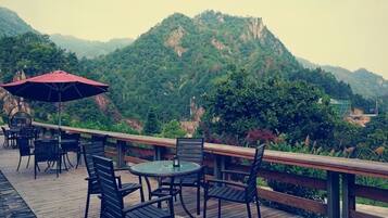 An outdoor seating area with tables and chairs, overlooking a mountainous landscape.