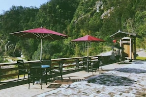 Sitzgelegenheit im Freien mit Sonnenschirmen, einer Holzterrasse und einer Bergkulisse.
