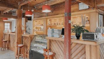 A wooden interior with a reception desk, bar stools, and a display case.