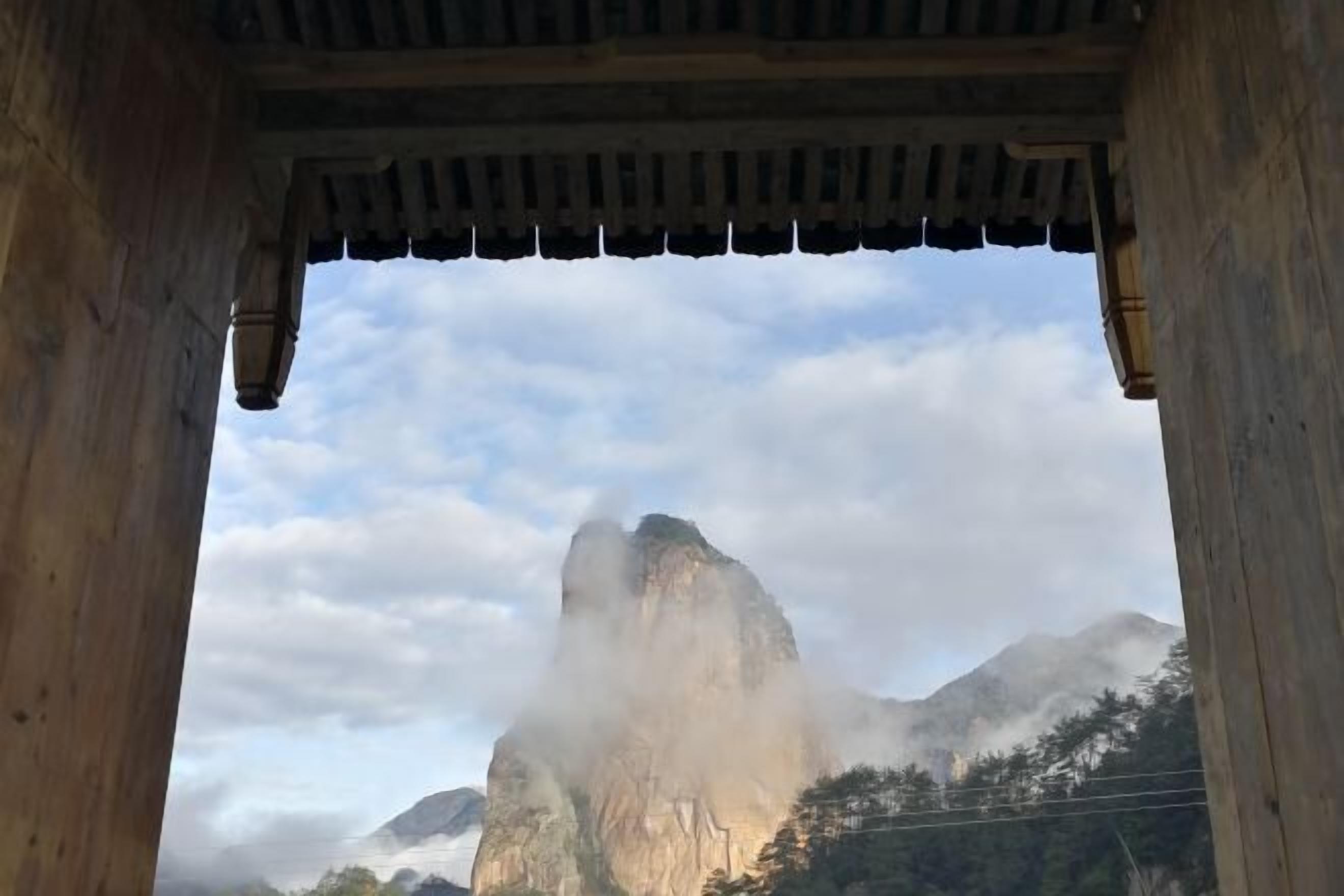 A mountain view through a wooden structure with a peaked roof.