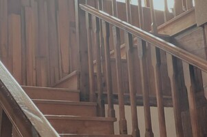 Una escalera de madera con barandilla, que lleva a un nivel superior.