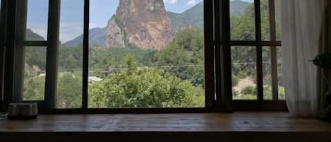 A room with a large window offering a view of a prominent rock formation and surrounding greenery.