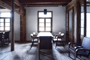Ein Zimmer mit einem langen Tisch, Stühlen, Holzböden und großen Fenstern.