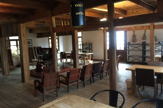 Un interior rústico con vigas de madera, mesas y sillas dispuestas para comer.
