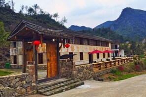 Un bâtiment traditionnel avec des fondations en pierre, des poutres en bois et un auvent rouge.