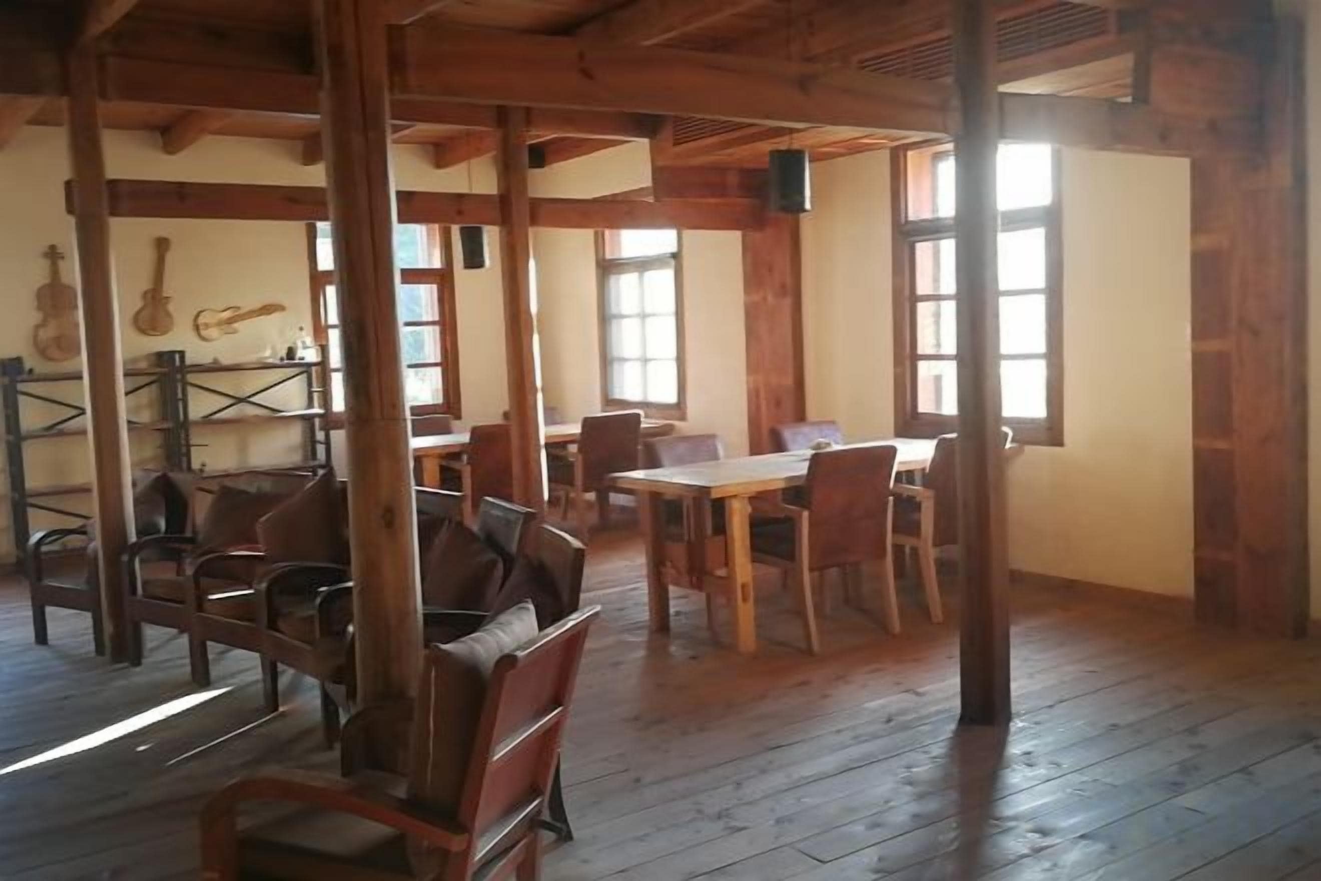 A rustic room with wooden floors, a dining table, chairs, and a guitar wall decoration.