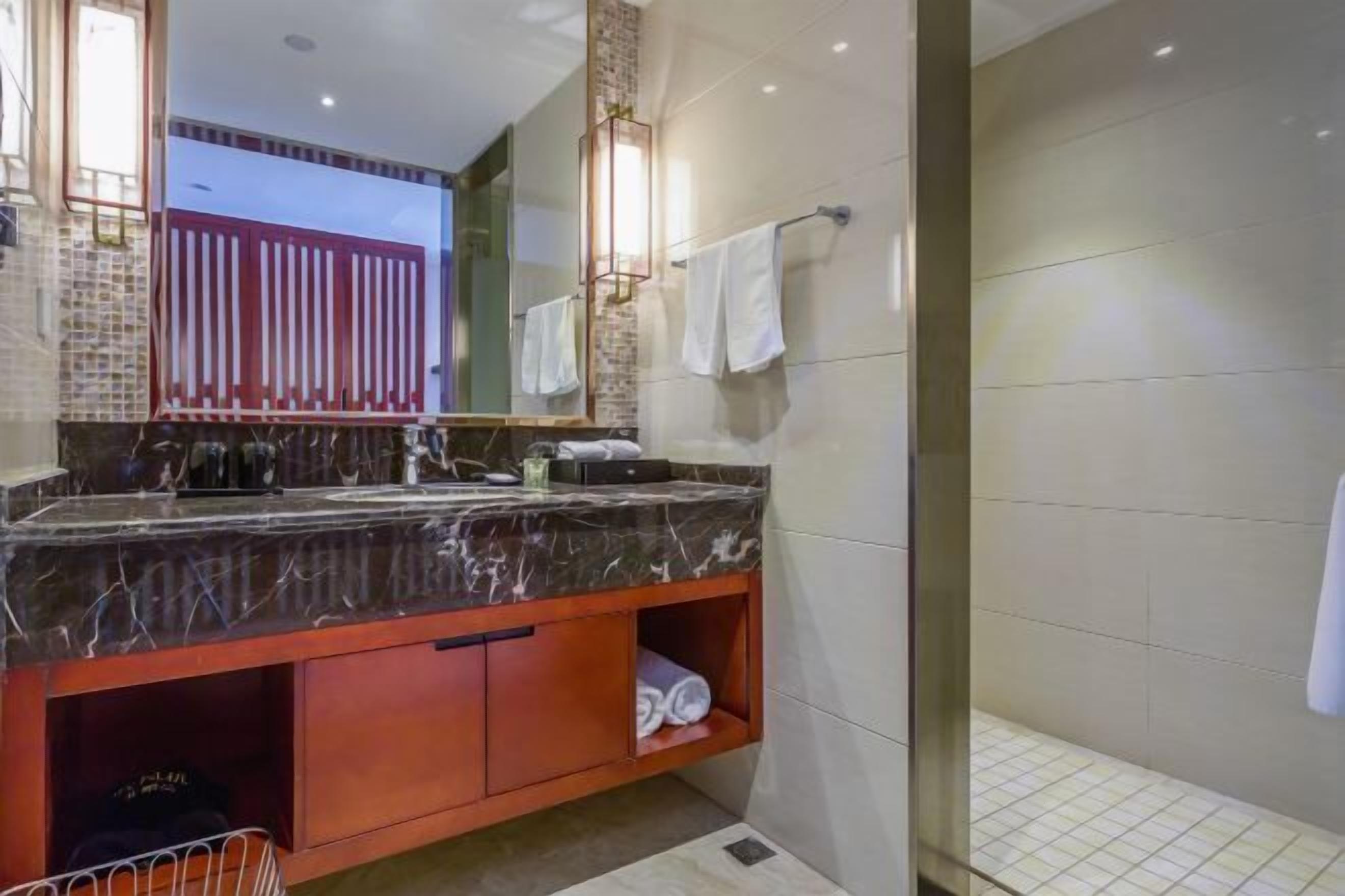 A modern bathroom with a marble sink, a glass shower enclosure, and a visible towel rack.