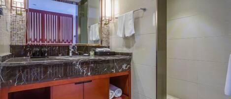 A modern bathroom with a marble sink, a glass shower enclosure, and a visible towel rack.