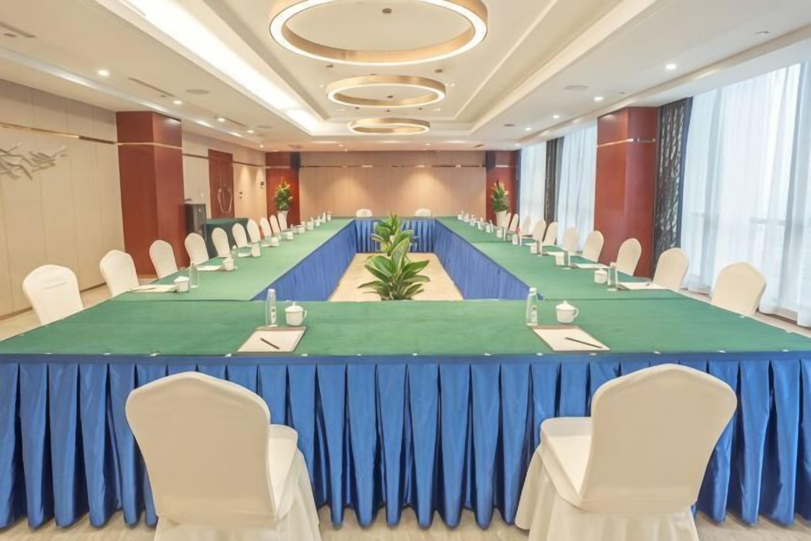 Une salle de conférence avec une longue table, des chaises et une nappe bleue.