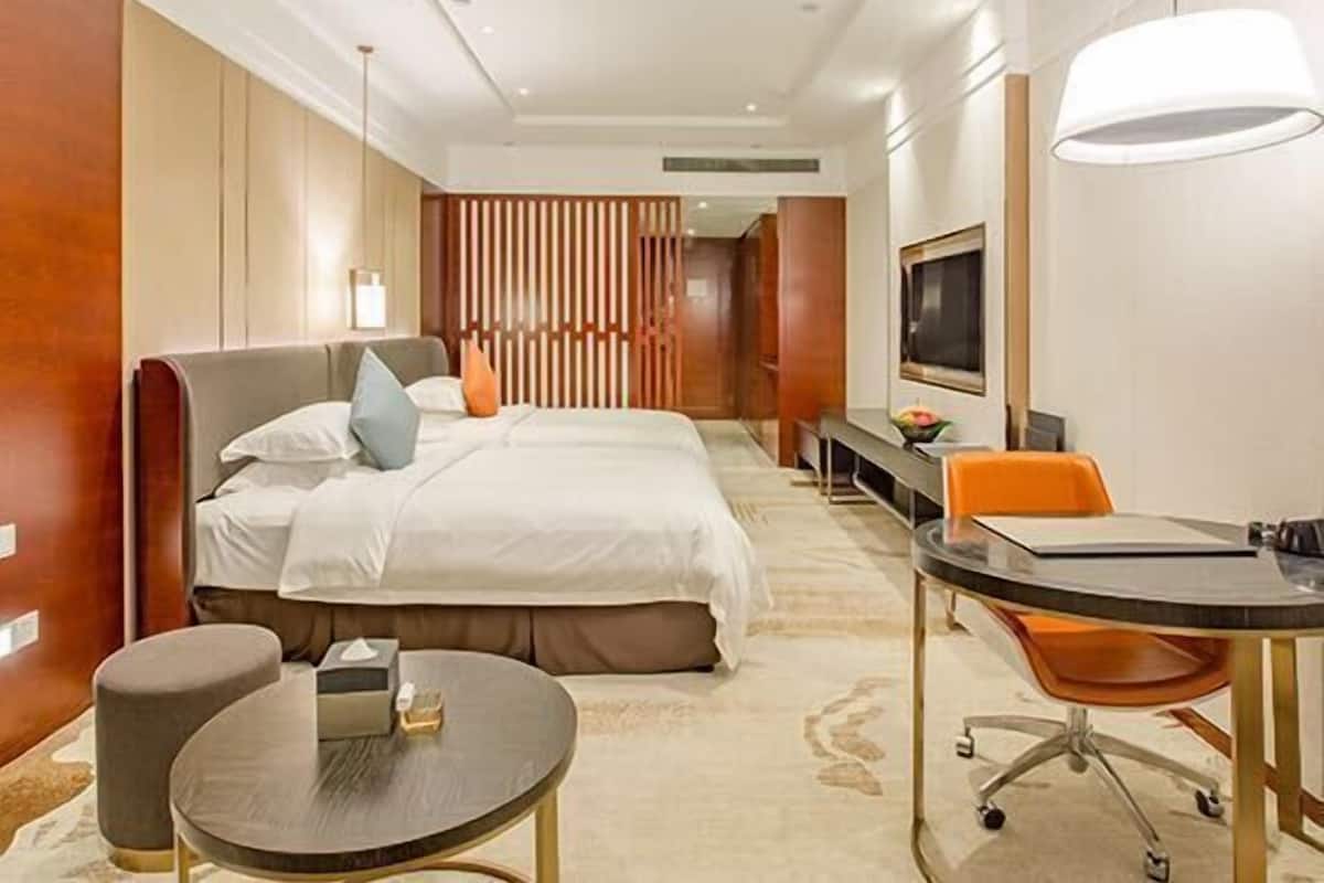 Una habitación de hotel con cama, mesita de noche, silla, escritorio y televisión.