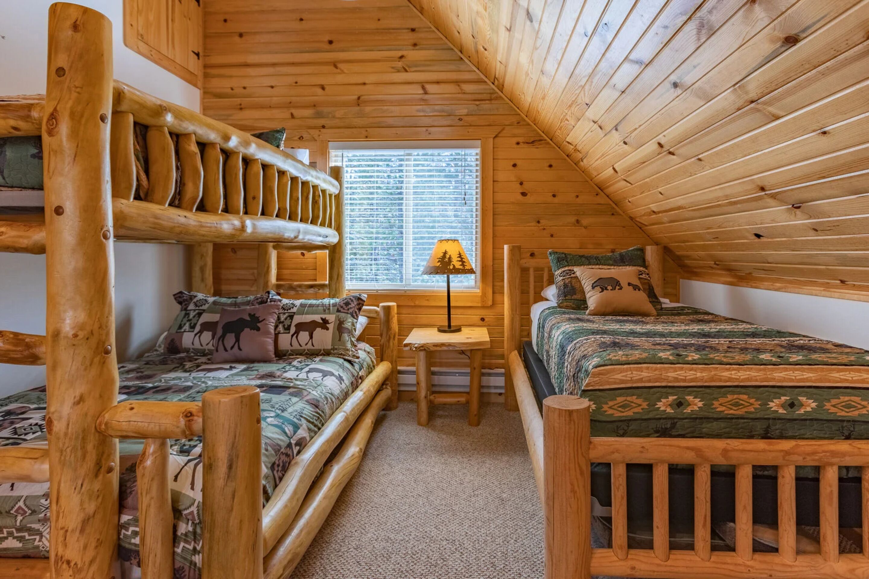 Een gezellig kamer in een blokhut met een stapelbed, een enkel bed en een kleine tafel.