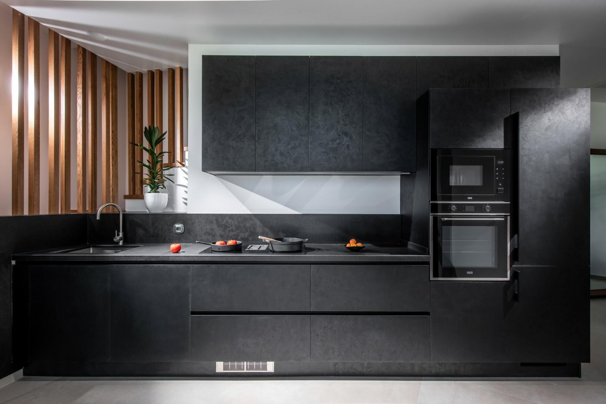 Una cucina moderna con mobili scuri, forno a incasso e microonde.