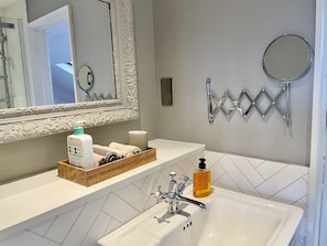A bathroom with a white sink, a mirror, a towel rack, and a soap dispenser.