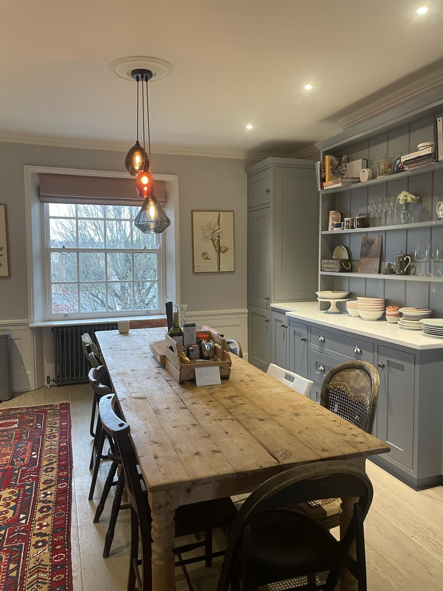 Una cocina con mesa de madera, sillas y una lámpara colgante.