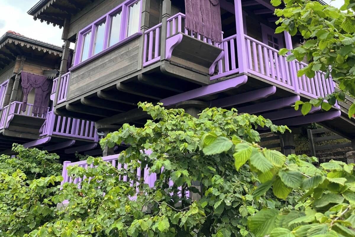 A two-story wooden house with purple accents and a balcony.