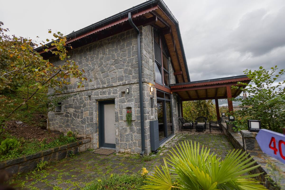 A stone building with a covered patio area, stone walls, and a small garden with a sign indicating the number 40.