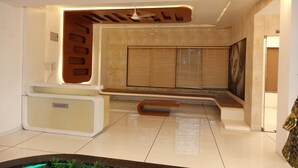 A modern reception area with a reception desk, a seating area, and a large window with blinds. - Chandan Van Club and Resort - Navsari (Navsari)