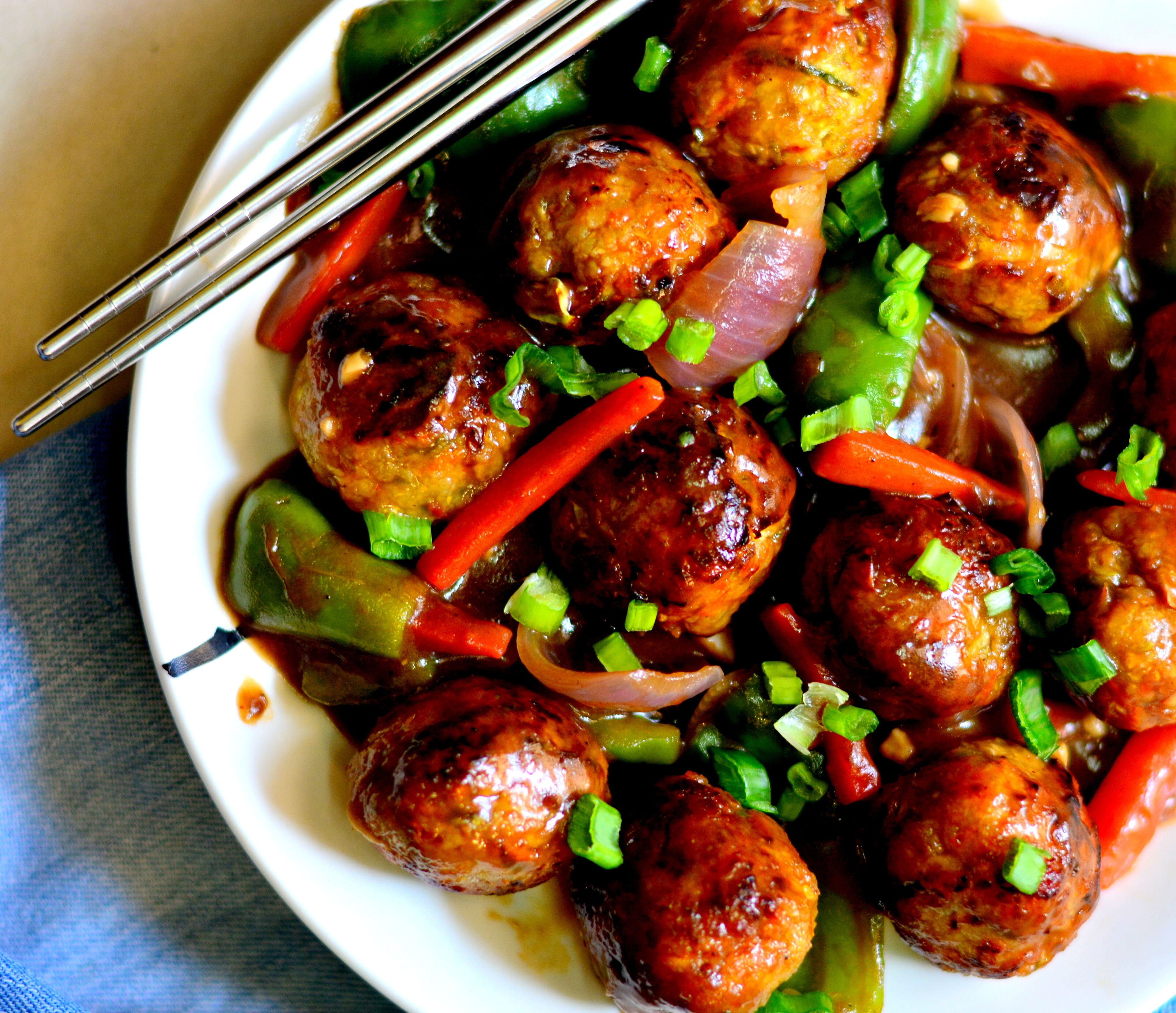 A plate of meatballs with vegetables and sauce.