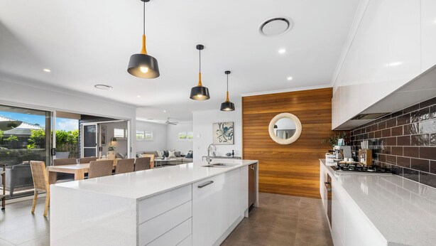 A modern kitchen with a central island, pendant lights, and a wooden accent wall. - Oasis at Sapphire,Pool, Pet Friendly, Bike Paths, Family Fun (Sapphire Beach)