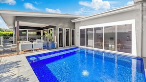 A modern house with a swimming pool, a covered patio, and a large sliding glass door. - Oasis at Sapphire,Pool, Pet Friendly, Bike Paths, Family Fun (Sapphire Beach)
