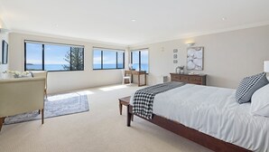 Ein geräumiges Schlafzimmer mit einem großen Bett, einem Schreibtisch und Meerblick.