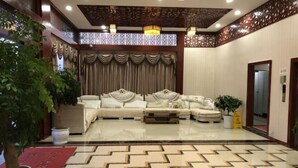 A spacious lobby with a large sofa set, a potted plant, and a patterned floor.