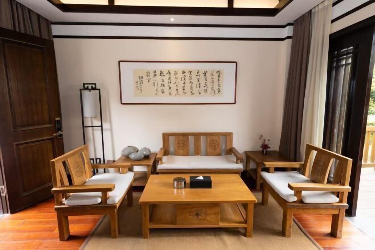 A traditional Japanese-style room with tatami flooring, wooden furniture, a low table, and a framed calligraphy piece on the wall.