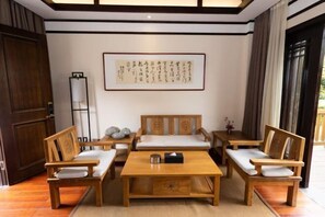 A traditional Japanese-style room with tatami flooring, wooden furniture, a low table, and a framed calligraphy piece on the wall.