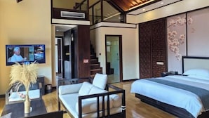 A modern hotel room with a large bed, a sofa, a TV, and a staircase leading to an upper level. - Zunyi Fengxiangyuan Hotel (Zunyi)