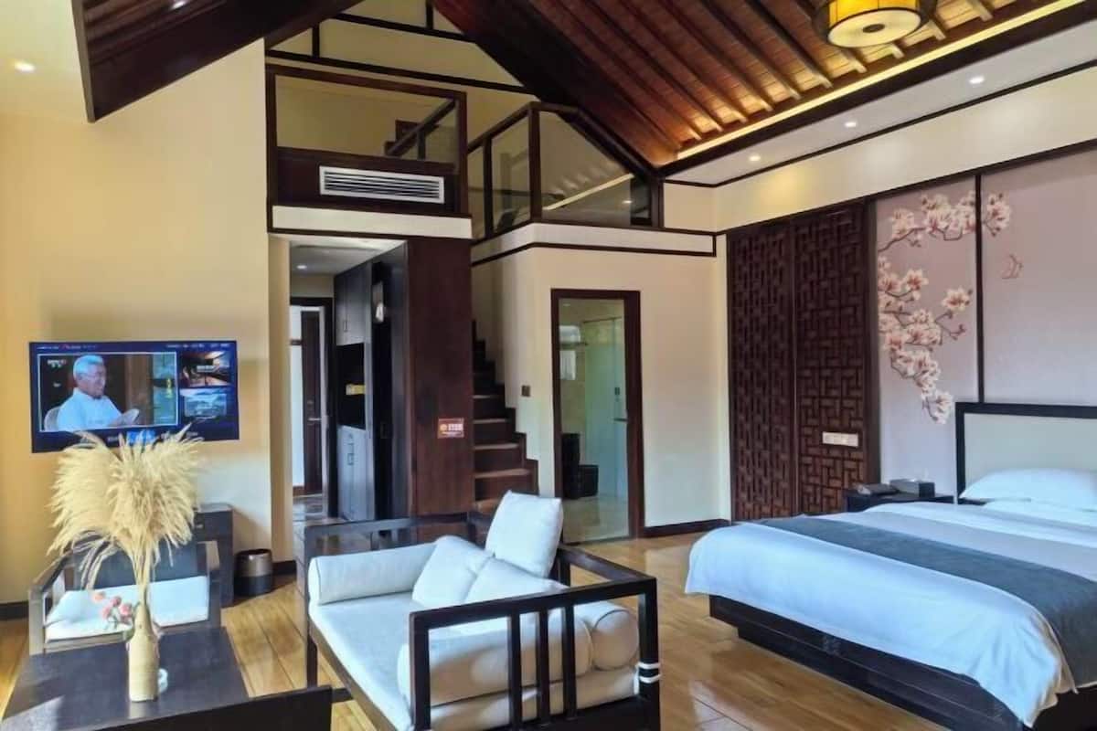 Une chambre d’hôtel moderne dotée d’un grand lit, d’un canapé, d’une télévision et d’un escalier menant à un niveau supérieur.