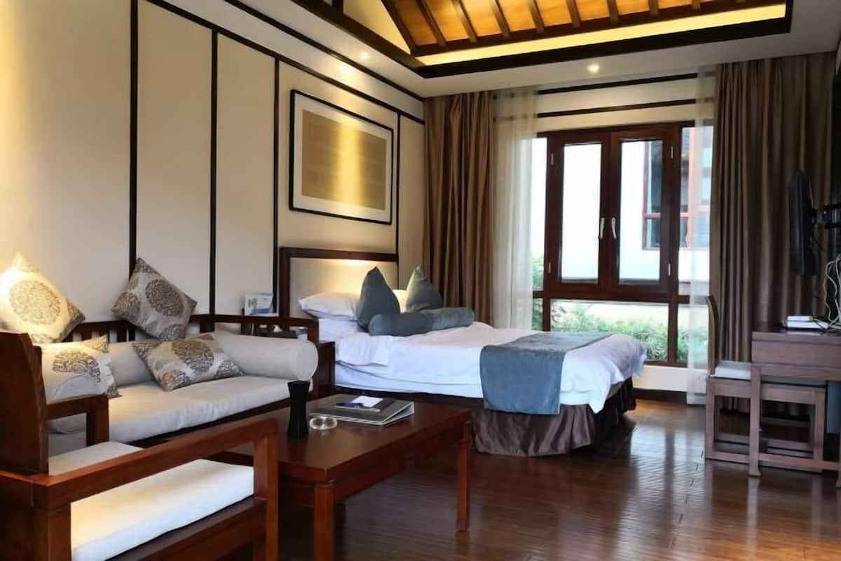 Une chambre d’hôtel avec un lit, un canapé, un bureau et une grande fenêtre avec des rideaux.