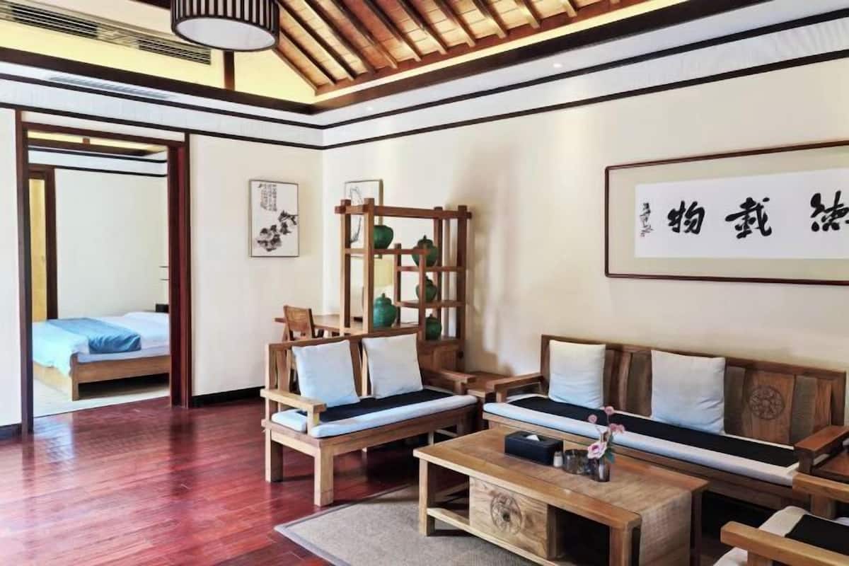 Une chambre au décor traditionnel, avec un lit, des meubles en bois et une œuvre calligraphique encadrée accrochée au mur.