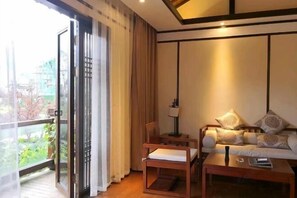A room with a sofa, a chair, a table, a lamp, and a sliding glass door leading to an outdoor area.