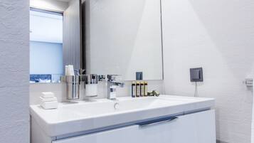 A modern bathroom with a white vanity, a large mirror, and a window providing a view.