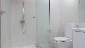 Un baño moderno con ducha envuelta en vidrio, inodoro y lavamanos.